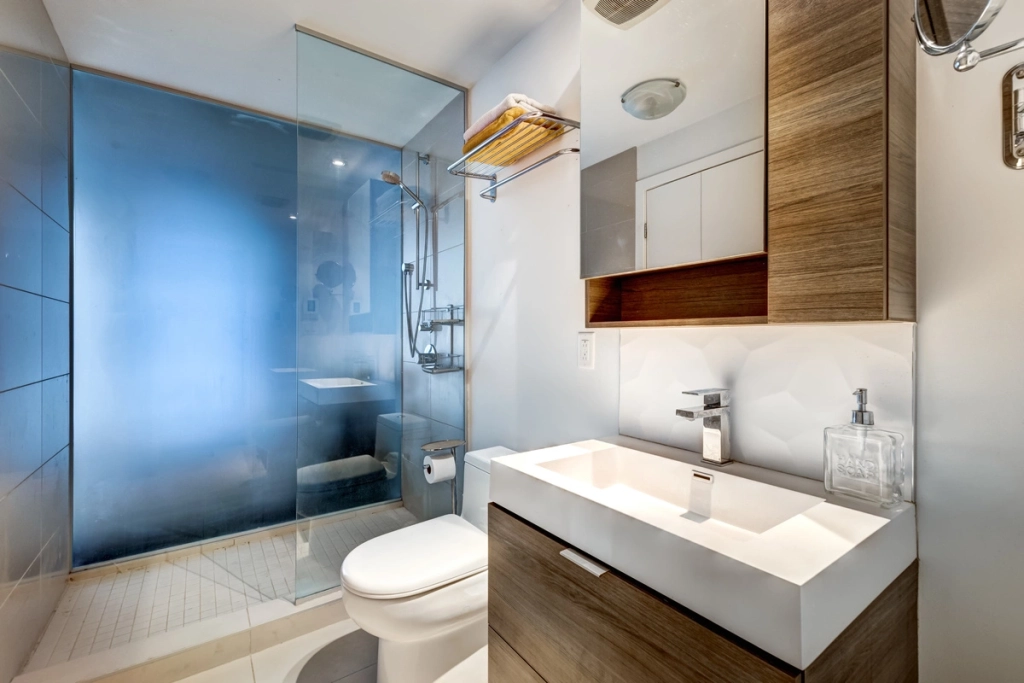 Salle de bains moderne avec une douche à paroi de verre, un meuble lavabo en bois et des accessoires de salle de bains haut de gamme.
