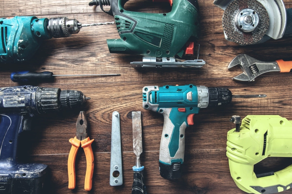 Ensemble d'outils de bricolage comprenant des perceuses, une scie sauteuse, une pince et d'autres outils à main sur une table en bois
