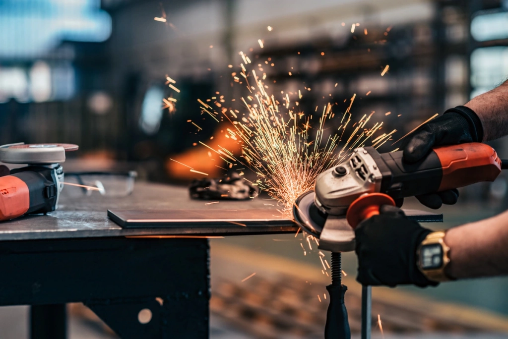 Homme utilisant une meuleuse d'angle avec des étincelles dans un atelier, montrant des outils électroportatifs en action